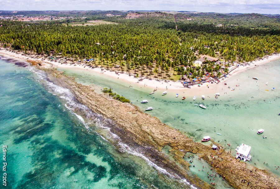 Igrejinha à beira-mar da Praia dos Carneiros cercada por coqueiros e piscinas naturais