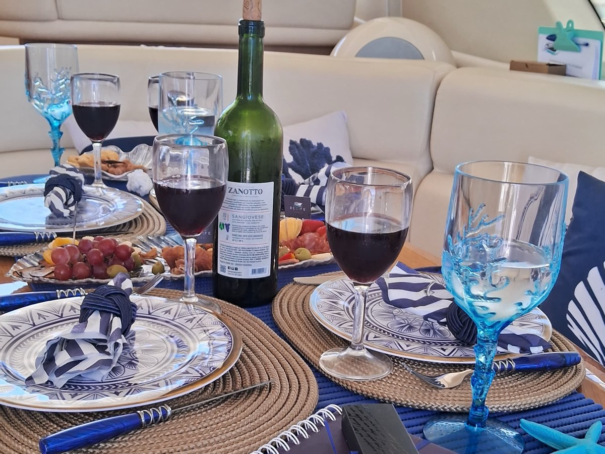 Mesa posta para jantar romântico a dois a bordo, com vinho e louça náutica azul